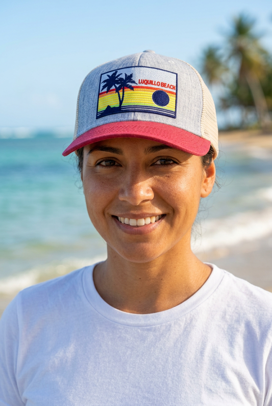 Luquillo Beach Rainbow Sunrise Cap modeled on the beach without the bill sticker